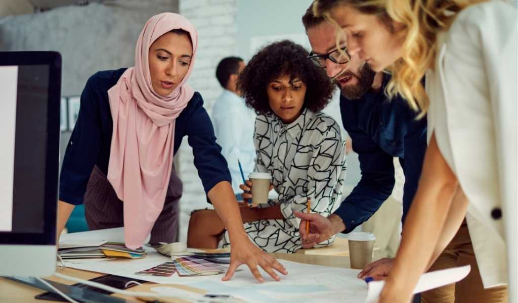 An image of people working collaboratively over a desk in an office.