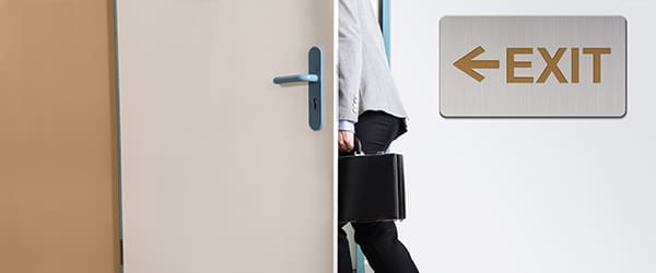 A man with a briefcase heading out a door with the word exit next to him.