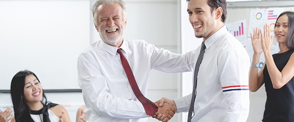 A group of 4 people in an office congratulating a man. Good relationships with employees