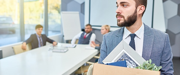 A man leaving an office with his belongings packed in a box - transition policies