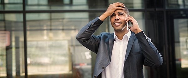 A man (employee) in a suit on a cell phone with a stressed look on his face.